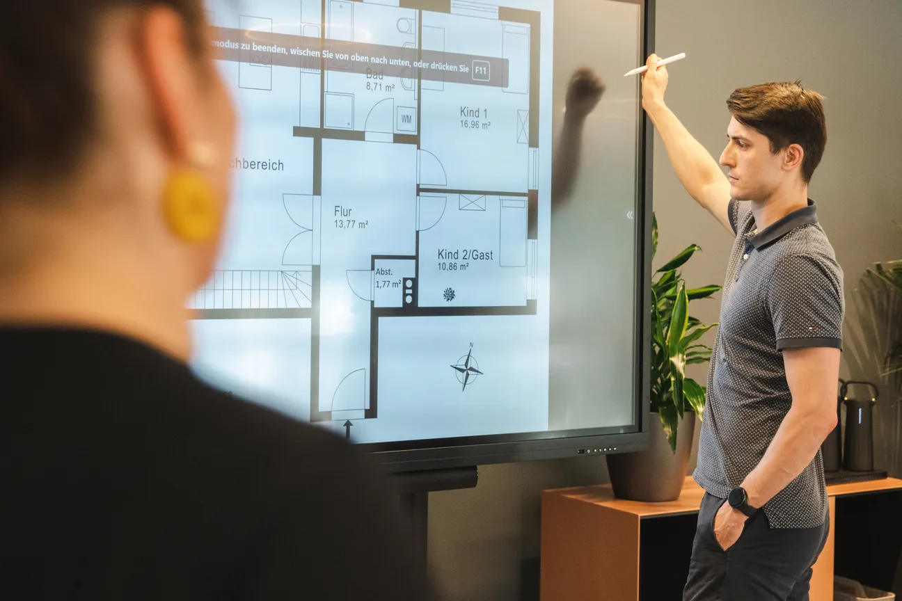 Mitarbeiter von Joppich & Rieckhoff skizziert einen Grundriss auf einem Whiteboard
